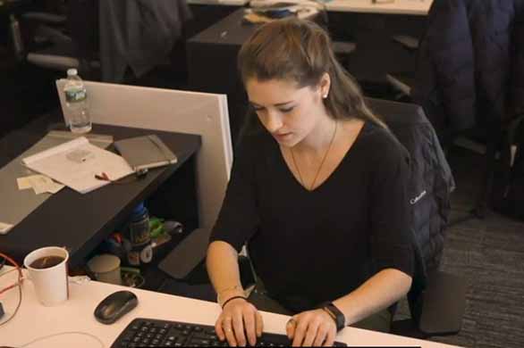 student working on keyboard at desk in office