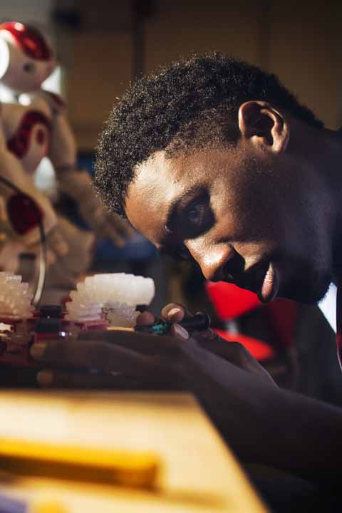 student closely looking at robotics pieces