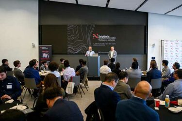 two people presenting at conference with others in audience sitting