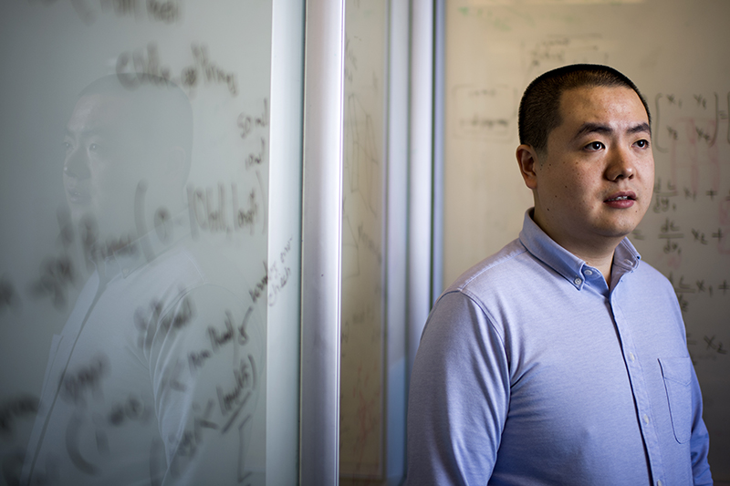 man standing sideways in front of white board with mathematical writing